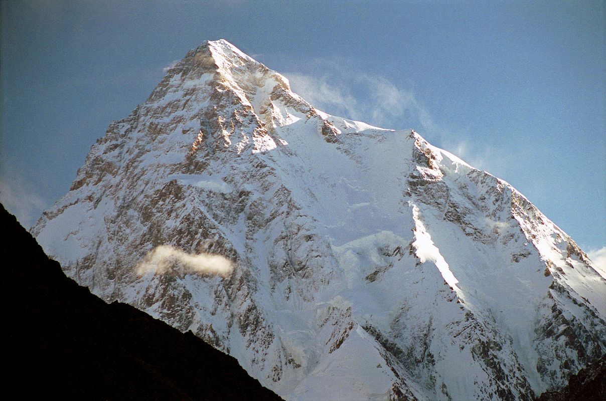 25 K2 Just After Sunrise From Concordia K2 shines in the early morning light from Concordia. The upper part of the K2 Southwest Pillar catches a bit of sun separating the west face in shadow from the sun descending the K2 South Face. The South-southeast Spur is partially in the sun and arrives at the K2 Shoulder on the right. On the far right is the Abruzzi Ridge / Spur, the East-southeast ridge, the normal ascent route. Called a suicidal route by Reinhold Messner, the K2 South Face or Polish Line was climbed for the first time on July 7, 1986 by Jerzy Kukuczka and Tadeusz Piotrowski. Piotrowski fell to his death on the descent.